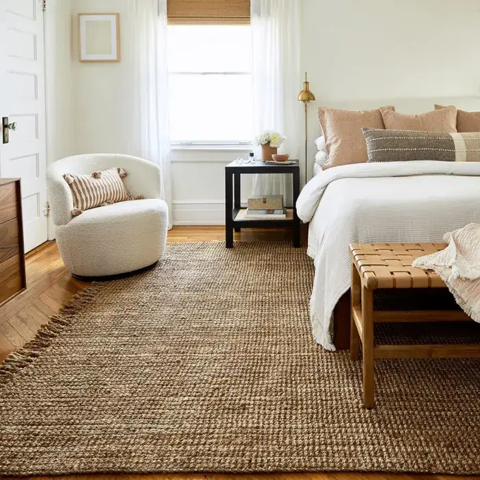 Bedroom with a jute carpet, a white bed, and a comfortable armchair
