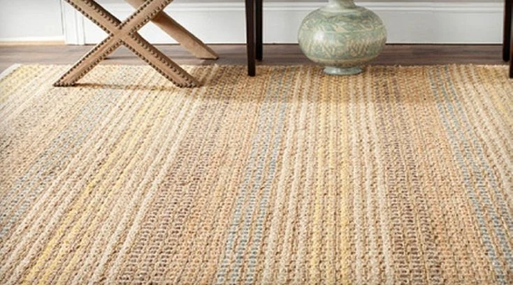 Close-up of a striped jute carpet with a vase and wooden stool