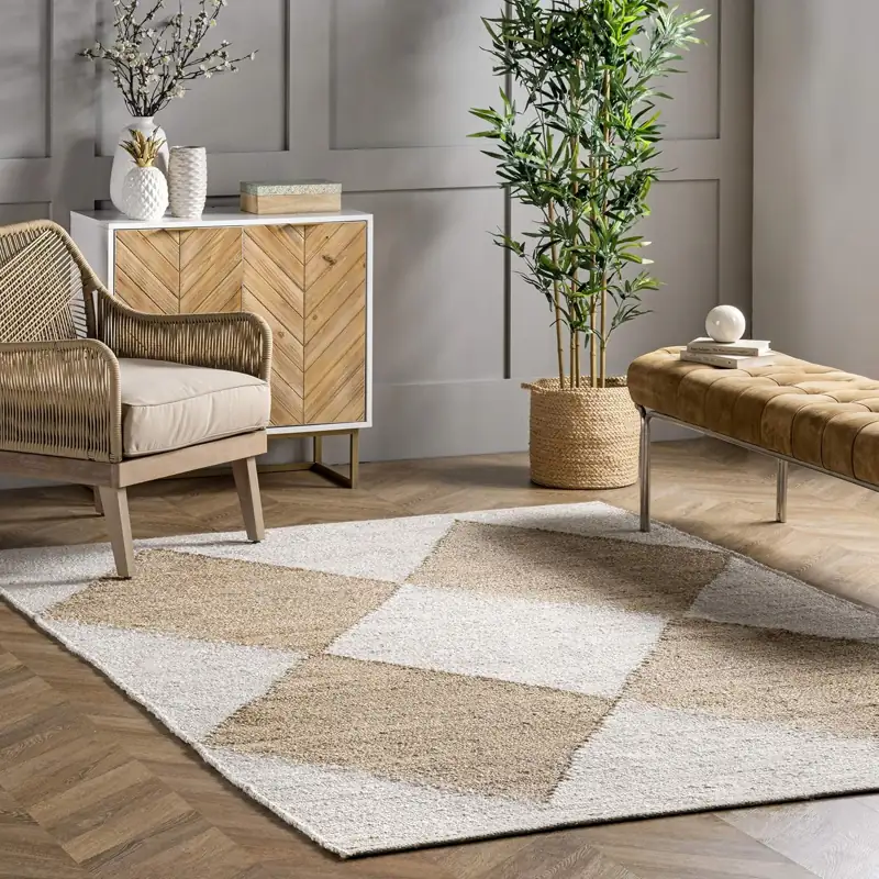 Living room with a checkered jute carpet a woven armchair and a wooden cabinet