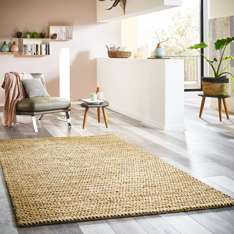 Spacious room with a jute carpet, a grey armchair, and a plant.